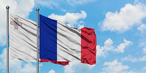 Malta and France flag waving in the wind against white cloudy blue sky together. Diplomacy concept, international relations.