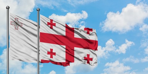 Malta and Georgia flag waving in the wind against white cloudy blue sky together. Diplomacy concept, international relations.
