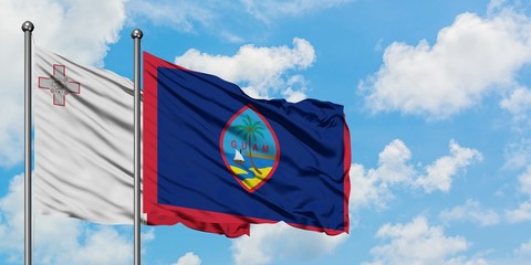 Malta and Guam flag waving in the wind against white cloudy blue sky together. Diplomacy concept, international relations.