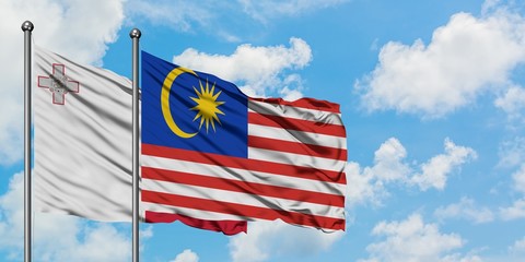 Malta and Malaysia flag waving in the wind against white cloudy blue sky together. Diplomacy concept, international relations.