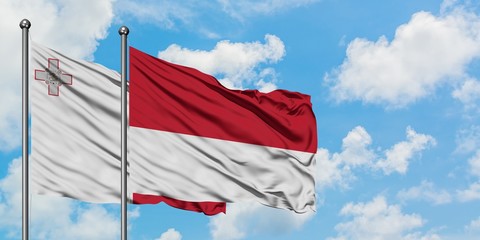 Malta and Monaco flag waving in the wind against white cloudy blue sky together. Diplomacy concept, international relations.