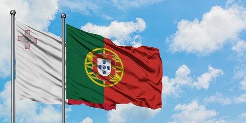 Malta and Portugal flag waving in the wind against white cloudy blue sky together. Diplomacy concept, international relations.