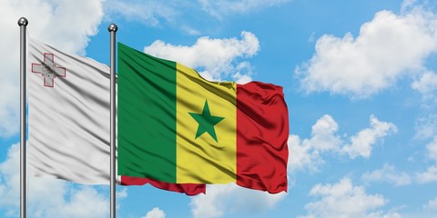 Malta and Senegal flag waving in the wind against white cloudy blue sky together. Diplomacy concept, international relations.