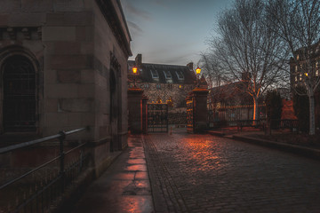 GLASGOW, SCOTLAND, DECEMBER 16, 2018: Beautiful cobbled street surrounded by old European style buildings. Illuminated only with weak light from street lamps.