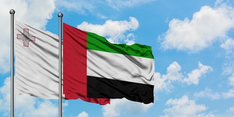 Malta and United Arab Emirates flag waving in the wind against white cloudy blue sky together. Diplomacy concept, international relations.