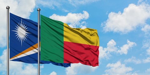 Marshall Islands and Benin flag waving in the wind against white cloudy blue sky together. Diplomacy concept, international relations.