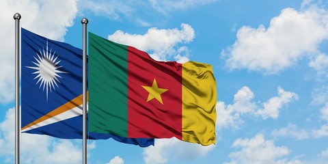 Marshall Islands and Cameroon flag waving in the wind against white cloudy blue sky together. Diplomacy concept, international relations.