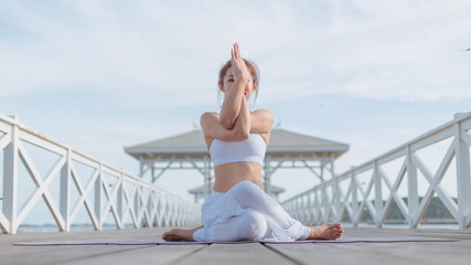 Young women practice yoga on the white bridge by the sea, the concept of enjoying privacy and the...