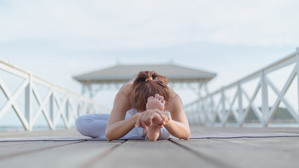 Young women practice yoga on the white bridge by the sea, the concept of enjoying privacy and the...