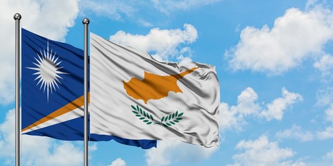 Marshall Islands and Cyprus flag waving in the wind against white cloudy blue sky together....