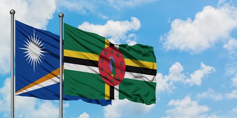 Marshall Islands and Dominica flag waving in the wind against white cloudy blue sky together. Diplomacy concept, international relations.