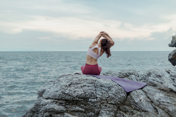 Young woman doing yoga exercise yoga master pose on the rock. Amazing yoga landscape in beautiful...