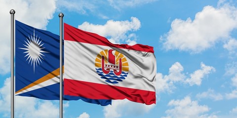 Marshall Islands and French Polynesia flag waving in the wind against white cloudy blue sky together. Diplomacy concept, international relations.