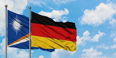 Marshall Islands and Germany flag waving in the wind against white cloudy blue sky together. Diplomacy concept, international relations.