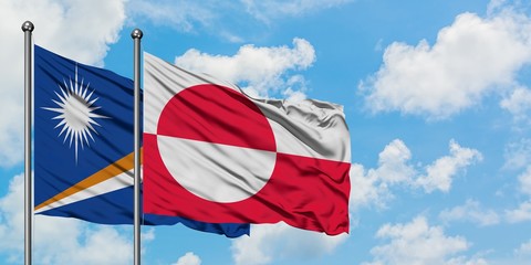 Marshall Islands and Greenland flag waving in the wind against white cloudy blue sky together. Diplomacy concept, international relations.