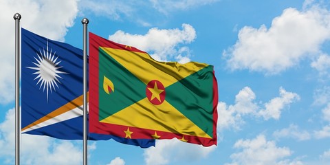 Marshall Islands and Grenada flag waving in the wind against white cloudy blue sky together. Diplomacy concept, international relations.