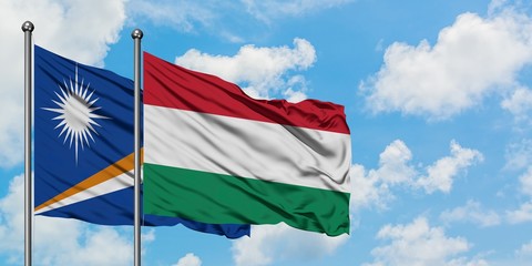 Marshall Islands and Hungary flag waving in the wind against white cloudy blue sky together. Diplomacy concept, international relations.