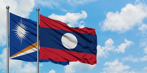 Marshall Islands and Laos flag waving in the wind against white cloudy blue sky together. Diplomacy concept, international relations.