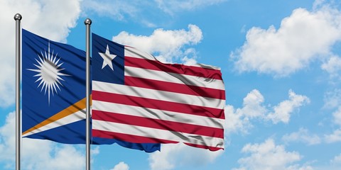 Marshall Islands and Liberia flag waving in the wind against white cloudy blue sky together. Diplomacy concept, international relations.