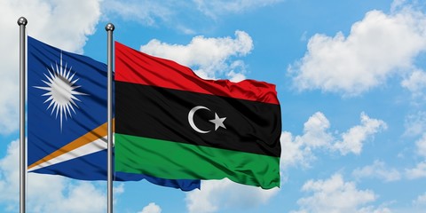 Marshall Islands and Libya flag waving in the wind against white cloudy blue sky together. Diplomacy concept, international relations.