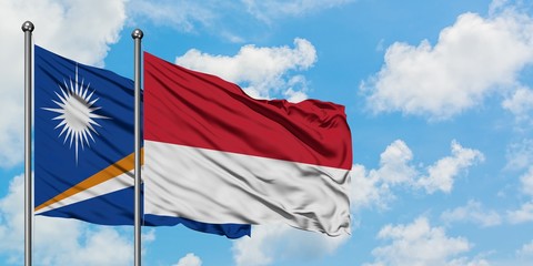 Marshall Islands and Monaco flag waving in the wind against white cloudy blue sky together. Diplomacy concept, international relations.