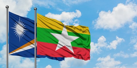 Marshall Islands and Myanmar flag waving in the wind against white cloudy blue sky together. Diplomacy concept, international relations.