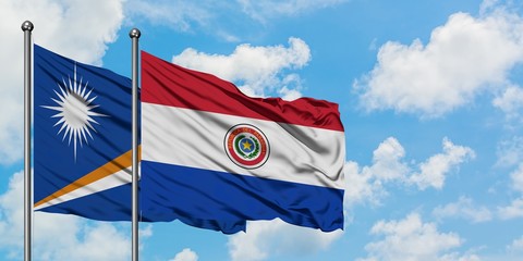 Marshall Islands and Paraguay flag waving in the wind against white cloudy blue sky together. Diplomacy concept, international relations.
