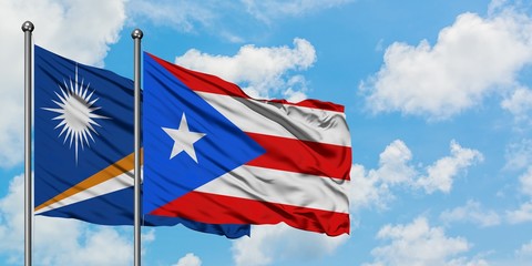 Marshall Islands and Puerto Rico flag waving in the wind against white cloudy blue sky together....