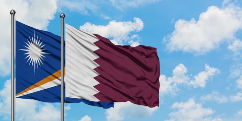Marshall Islands and Qatar flag waving in the wind against white cloudy blue sky together....