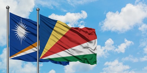 Marshall Islands and Seychelles flag waving in the wind against white cloudy blue sky together. Diplomacy concept, international relations.