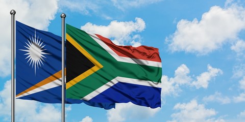 Marshall Islands and South Africa flag waving in the wind against white cloudy blue sky together. Diplomacy concept, international relations.