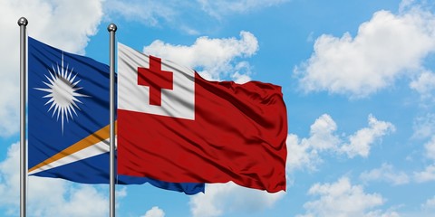Marshall Islands and Tonga flag waving in the wind against white cloudy blue sky together. Diplomacy concept, international relations.