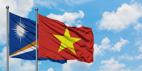 Marshall Islands and Vietnam flag waving in the wind against white cloudy blue sky together. Diplomacy concept, international relations.