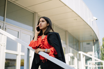 Fototapeta premium Young business woman leaning on railing outside office