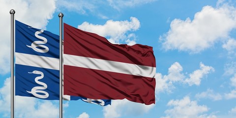 Martinique and Latvia flag waving in the wind against white cloudy blue sky together. Diplomacy concept, international relations.