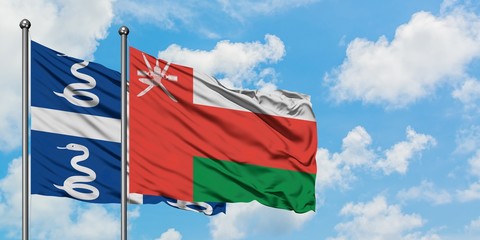 Martinique and Oman flag waving in the wind against white cloudy blue sky together. Diplomacy concept, international relations.
