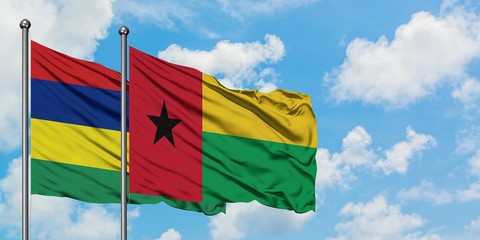 Mauritius and Guinea Bissau flag waving in the wind against white cloudy blue sky together. Diplomacy concept, international relations.