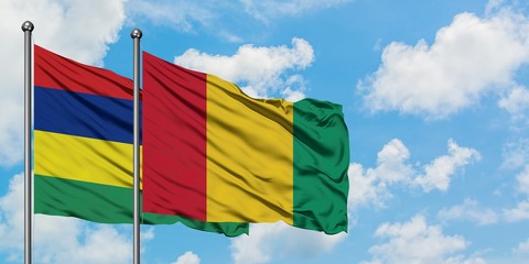 Mauritius and Guinea flag waving in the wind against white cloudy blue sky together. Diplomacy...