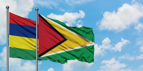 Mauritius and Guyana flag waving in the wind against white cloudy blue sky together. Diplomacy concept, international relations.
