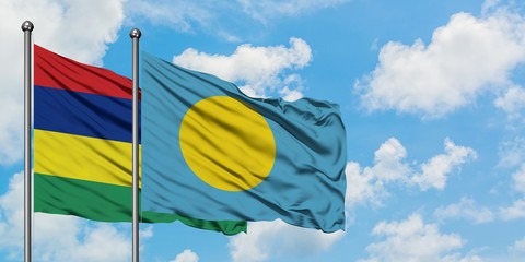 Mauritius and Palau flag waving in the wind against white cloudy blue sky together. Diplomacy concept, international relations.