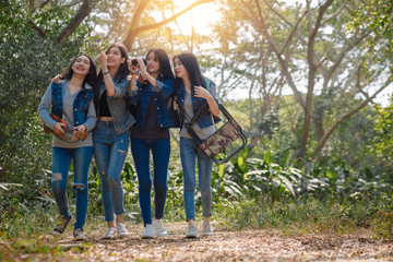 Low angle close up photo of four friends enjoying the beauty of nature, hiking in wild forest, looking for a nice place for camp, smiling, exploring, jungle trail
