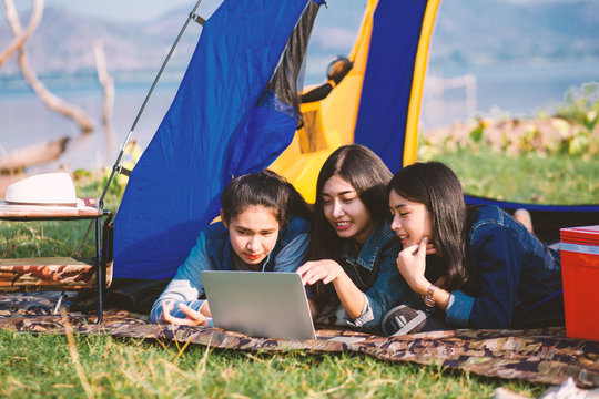 Lovely young tourists relax with rivers and mountains, pick up notebooks, see pictures, camping today, enjoy mountain climbing and holidays camping and tarvel concept.