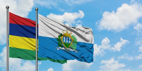 Mauritius and San Marino flag waving in the wind against white cloudy blue sky together. Diplomacy concept, international relations.