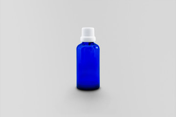 Empty blue glass bottle for essential oil and cosmetic products isolated on soft gray background