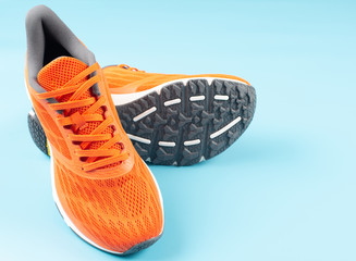 Orange sport shoes on a blue background. Concept for good health.