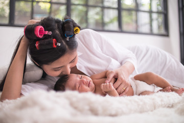 Beautiful young mother with her newborn baby lying in bedroom