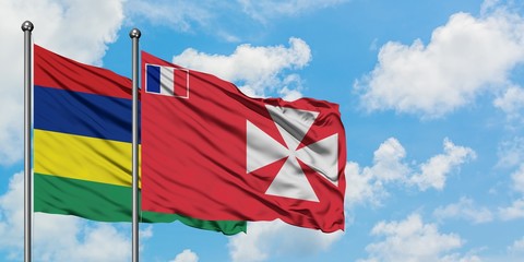 Mauritius and Wallis And Futuna flag waving in the wind against white cloudy blue sky together. Diplomacy concept, international relations.