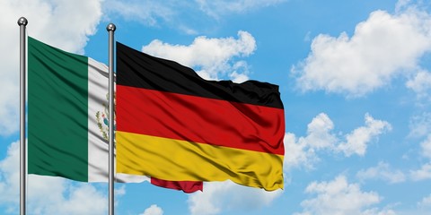 Mexico and Germany flag waving in the wind against white cloudy blue sky together. Diplomacy concept, international relations.