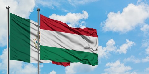 Mexico and Hungary flag waving in the wind against white cloudy blue sky together. Diplomacy concept, international relations.