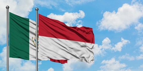 Mexico and Indonesia flag waving in the wind against white cloudy blue sky together. Diplomacy concept, international relations.